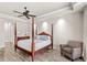 Comfortable main bedroom featuring a tray ceiling, four-poster bed, and cozy seating area at 2825 Lakeshore Dr, Mount Dora, FL 32757