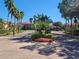 Gated community entrance with lush landscaping, palms, and well-maintained brick pavers at 2860 Falconhill Dr, Apopka, FL 32712