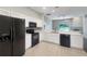 Modern kitchen featuring white cabinets, black appliances, light countertops and tile flooring at 30442 Pga Dr, Sorrento, FL 32776