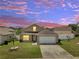 Beautiful sunset view of home with a well-manicured lawn at 5118 Luna Negra Dr, Orlando, FL 32811