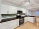Modern kitchen with white cabinets, stainless steel appliances, dark countertops and open access to living area at 553 Floral Dr, Kissimmee, FL 34743