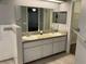 Bathroom featuring double sinks, granite countertops, walk-in closet and modern fixtures at 6419 Borg St, Leesburg, FL 34748