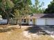 Charming yellow home with a white garage door, front door, and mature trees at 6508 Coral Cove Dr, Orlando, FL 32818