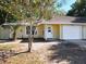 Inviting yellow home features a well-maintained lawn, a garage, and a cozy entryway at 6508 Coral Cove Dr, Orlando, FL 32818