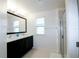 Bathroom with dual sinks, large mirror, walk-in shower, and natural light at 8016 Sweet Orange Ave, Winter Garden, FL 34787