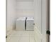 Bright laundry room featuring a washer, dryer, white tile flooring, and a wire shelf for storage at 8016 Sweet Orange Ave, Winter Garden, FL 34787
