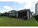 An exterior view of the home's rear, featuring a screened-in patio and lush green lawn at 8742 Peachtree Park Ct, Windermere, FL 34786
