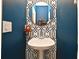 Stylish powder room featuring a pedestal sink with patterned wall and round mirror at 9573 Southern Garden Cir, Altamonte Springs, FL 32714