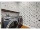 Laundry room with trendy wallpaper, washer, dryer, and wooden shelf at 1005 Talon Pl, Winter Springs, FL 32708