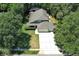 Aerial view of a house with a long driveway and three-car garage surrounded by lush trees at 1101 N Division St, Oviedo, FL 32765