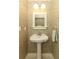 Charming powder room with pedestal sink, decorative wallpaper, sconce lighting and a white framed mirror at 1101 N Division St, Oviedo, FL 32765