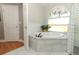 A soaking tub situated under a window and next to a glass-enclosed shower at 1101 N Division St, Oviedo, FL 32765