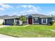 Inviting home with a bright red door, lush green lawn, and mature palm tree at 13606 Summer Rain Dr, Orlando, FL 32828
