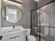 Modern bathroom features sleek gray tile, round mirror, and glass-enclosed shower with modern fixtures at 16808 Bolsena Dr, Bella Collina, FL 34756