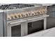 Close-up of a chef's stainless steel range with double ovens, multiple burners, and premium brass knobs at 16808 Bolsena Dr, Bella Collina, FL 34756