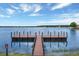 Peaceful lake view with a wooden dock, blue sky, and serene atmosphere at 16808 Bolsena Dr, Bella Collina, FL 34756