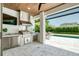 Outdoor kitchen featuring stainless steel appliances, marble counters, a wood ceiling, and a view of the pool at 1700 Palm Ave, Winter Park, FL 32789