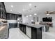 Open-concept kitchen with granite countertops, modern appliances, dark cabinetry and seamless flow to the living room at 210 Hydra Way, Groveland, FL 34736