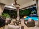 Inviting covered patio featuring comfortable seating near a sparkling pool with ambient lighting and privacy landscaping at 2171 Forrest Rd, Winter Park, FL 32789