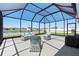 Enclosed patio with gray concrete, screened roof, and white wicker furniture at 236 Aquamarine Ln, Kissimmee, FL 34758