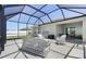A screened-in porch has a wicker couch and lounge chairs at 236 Aquamarine Ln, Kissimmee, FL 34758