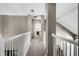 Upstairs hallway with carpet and white railings; doorway leads to a bedroom with a bed and nightstand at 2424 Antlia Dr, Orlando, FL 32828