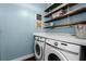 Well-lit laundry area with a front-loading washer and dryer, complemented by open shelving with neatly folded towels at 2424 Antlia Dr, Orlando, FL 32828