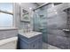 Bathroom featuring blue textured tiled walls, glass shower door, vanity with drawers, and a toilet at 2623 Parsley Dr, Orlando, FL 32837