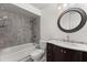 Well-lit bathroom featuring a tub with tiled walls and a vanity with a marble countertop and dark wood cabinets at 2623 Parsley Dr, Orlando, FL 32837