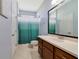 Bathroom with a single sink vanity, a large mirror, and a shower-tub combination with a green curtain at 26712 Augusta Springs Cir, Leesburg, FL 34748