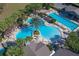 Aerial view of the community pool featuring a unique design, lush landscaping, and poolside amenities at 26712 Augusta Springs Cir, Leesburg, FL 34748