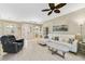 Bright living room featuring a white sectional sofa, tile flooring, and a modern ceiling fan at 26712 Augusta Springs Cir, Leesburg, FL 34748