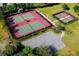 Aerial view of the tennis and pickleball courts surrounded by lush landscaping and a parking area at 26712 Augusta Springs Cir, Leesburg, FL 34748