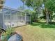 Backyard featuring a screened-in enclosure on the patio with mature trees and grass at 3020 Zaharias Dr, Orlando, FL 32837