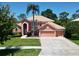 Two-story home boasting a tile roof, three-car garage, mature palm tree, and well-manicured landscaping at 3020 Zaharias Dr, Orlando, FL 32837