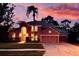 Charming two-story home with a well-manicured lawn, mature trees and a colorful, vibrant sunset in the background at 3020 Zaharias Dr, Orlando, FL 32837