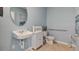 Powder blue bathroom features a round mirror, accessible grab bar, and neutral-toned tile at 33640 Seattle Slew Dr, Sorrento, FL 32776