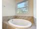 Modern bathtub with a window above and light brown geometric patterned tile surround at 341 Bahia Cir, Longwood, FL 32750