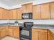 Efficient kitchen with black appliances, wooden cabinets, and granite countertops at 3908 Coastal Breeze Dr, Kissimmee, FL 34744
