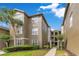 Exterior of the condominium building featuring lush landscaping, brick accents and a palm tree at 420 Summit Ridge Pl # 112, Longwood, FL 32779