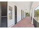 Covered porch with brick flooring, white pillars, black shutters, and multiple entry doors at 4232 Spring Ln, Lakeland, FL 33811