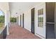 Covered porch with brick flooring, white pillars, black shutters, and multiple doors along the exterior at 4232 Spring Ln, Lakeland, FL 33811