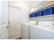 Bright laundry room featuring a washer, dryer, storage shelves, and white door at 428 Orista Dr, Davenport, FL 33897