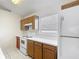 Cozy kitchen with wood cabinets, white appliances, tile flooring, and a bright window at 50989 Highway 27 # 174, Davenport, FL 33897