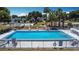 An aerial view of a sparkling pool surrounded by palm trees, lounge chairs, and community amenities at 50989 Highway 27 # 174, Davenport, FL 33897