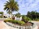 The Enclaves Amenity Center entryway with lush landscaping, mature palm trees, and blue skies at 646 Longboat Dr, Davenport, FL 33896