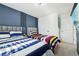 Bright bedroom features two beds with striped bedding, a navy accent wall, and a modern television at 646 Longboat Dr, Davenport, FL 33896