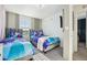 Bright bedroom featuring two twin beds, themed bedding, a mounted TV, and minimalist decor at 646 Longboat Dr, Davenport, FL 33896