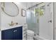 Bright bathroom featuring a navy vanity, round mirror, and glass-enclosed shower at 8440 Woburn Ct, Windermere, FL 34786