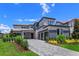Elegant two-story home with stone accents, a glass balcony, three-car garage, and a paved driveway at 16825 Bolsena Dr, Montverde, FL 34756